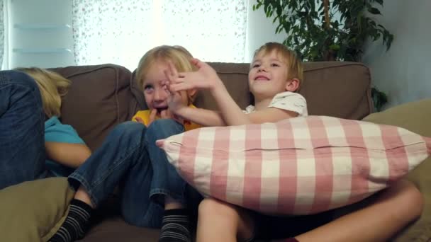 Anak-anak saudara duduk di sofa dan menonton TV — Stok Video