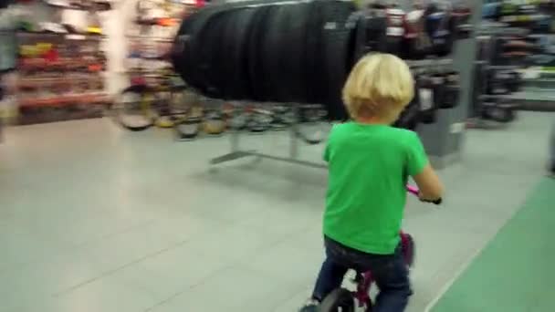 Boy testing en paardrijden fiets in de sportwinkel — Stockvideo