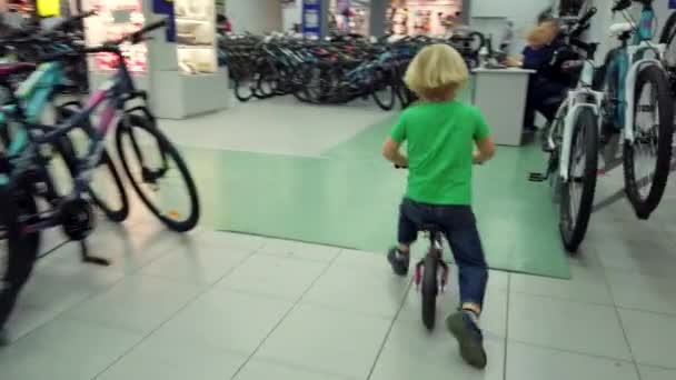 Boy testing en paardrijden fiets in de sportwinkel — Stockvideo