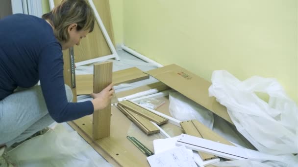 Mujer blanca de mediana edad está montando muebles — Vídeos de Stock