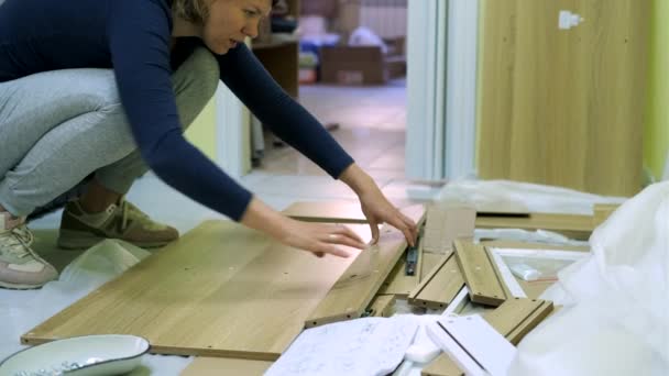 Weiße Frau mittleren Alters baut Möbel zusammen — Stockvideo