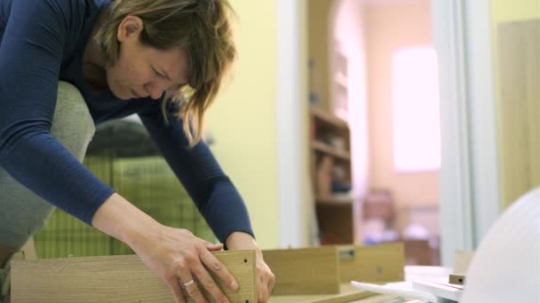 Mujer blanca de mediana edad está montando muebles — Vídeos de Stock