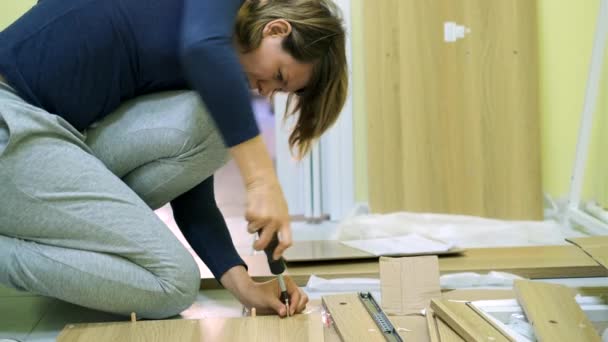 Mujer blanca de mediana edad está montando muebles — Vídeos de Stock