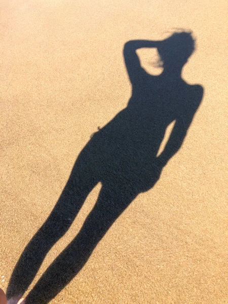 Young woman shadow on a sand