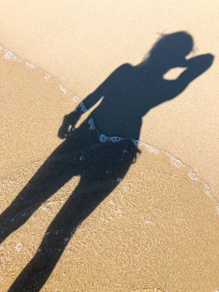 Young woman shadow on a sand