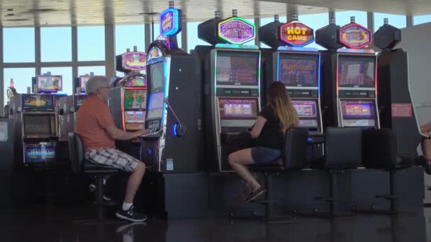 Mensen spelen gokkasten op de luchthaven — Stockvideo