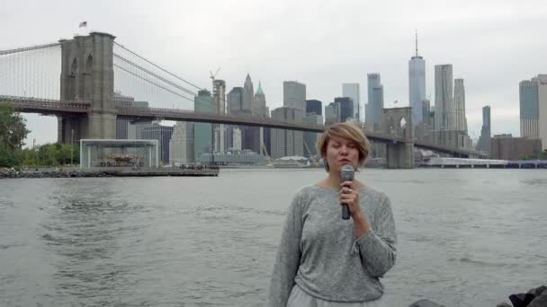 Junge TV-Reporterin sendet vor dem Hintergrund von Hochhäusern in Manhattan — Stockvideo