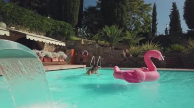 Pembe flamingo ile eğlenen genç kadın