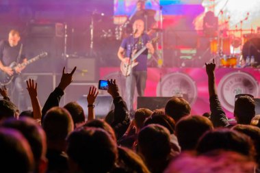 Canlı rock müzik konserinde müzisyenleri sahnede alkışlayan hayranlar