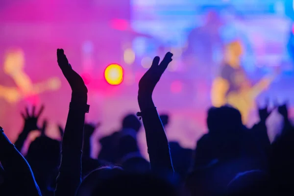 Fans cheering musicians on stage at live rock music concert