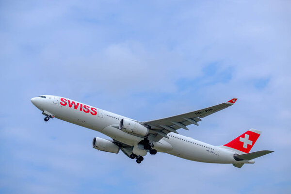 Самолеты швейцарских авиалиний готовятся к посадке в дневное время в международном аэропорту
