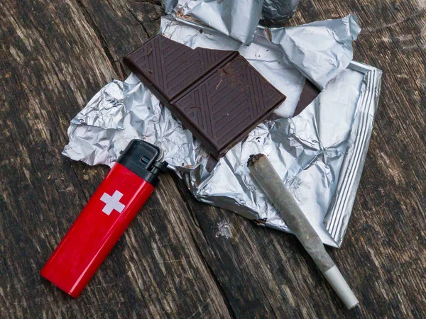 Dark chocolate, swiss lighter and joint with marijuana