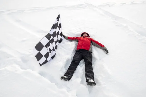L'homme gît dans la neige avec le drapeau d'arrivée — Photo