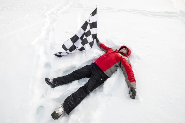 Ο άνθρωπος κείτεται στο χιόνι με τη σημαία του τερματισμού — Φωτογραφία Αρχείου