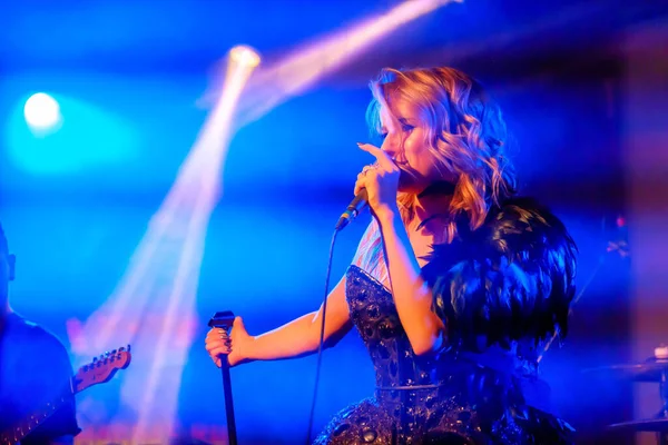 Girl singer sings on stage holding microphone