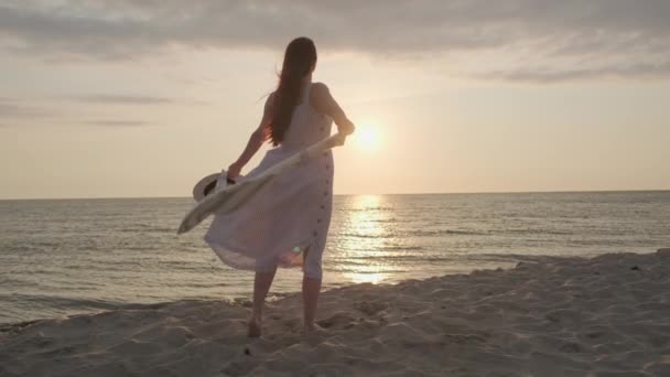 Femme anonyme profitant d'une journée venteuse pendant le coucher du soleil sur la plage — Video