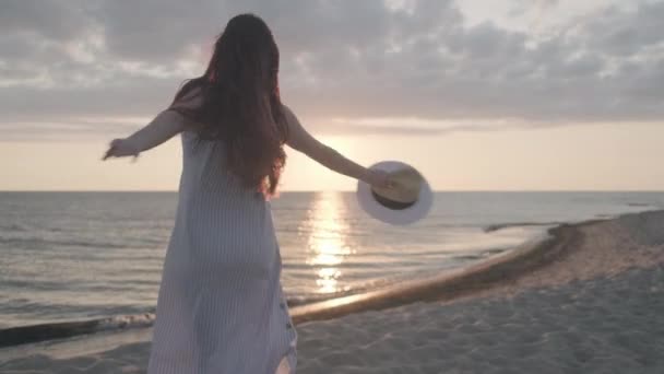 Щаслива жінка танцює на пляжі під час заходу сонця — стокове відео