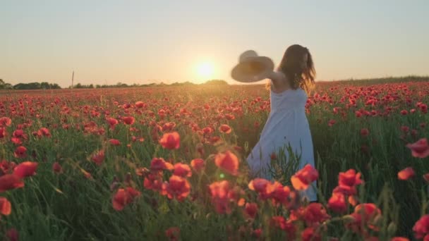 Улыбающаяся женщина в шляпе танцует на цветущем лугу — стоковое видео