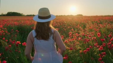 Çiçekli çayırlarda yürüyen tanınmayan bir kadın.