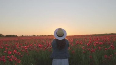 Gün batımında yapraklarla oynayan tanınmayan bir kadın.