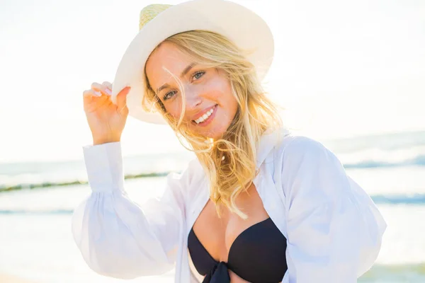 Bikini giyen ve plajda şapka takan mutlu bir kadın. — Stok fotoğraf