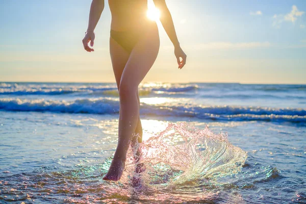 Mulher espirrando água andando em seasidev — Fotografia de Stock