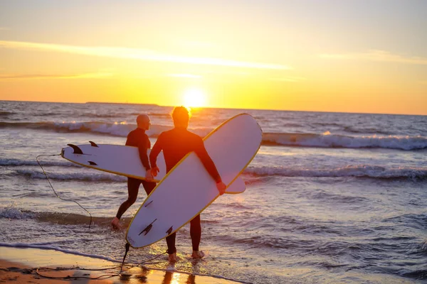 Surfisti irriconoscibili che entrano in mare ondulato — Foto Stock