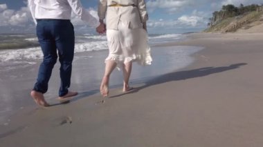 Kumsalda yürüyen romantik bir çift.