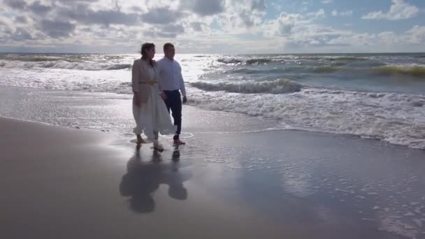 Casal recém-casado caminhando ao longo do mar ondulando — Vídeo de Stock