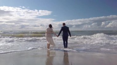 Mutlu gelin ve damat deniz dalgalarının üzerinden atlıyor