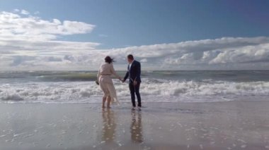 Deniz dalgalarının üzerinden atlayan mutlu yeni evli çift