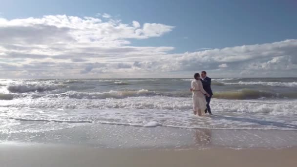 Pasangan pengantin baru yang lembut berdiri di laut melambaikan tangan dan berciuman — Stok Video