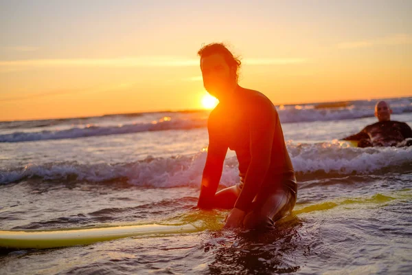 Surfer siedzi na desce surfingowej w morzu — Zdjęcie stockowe