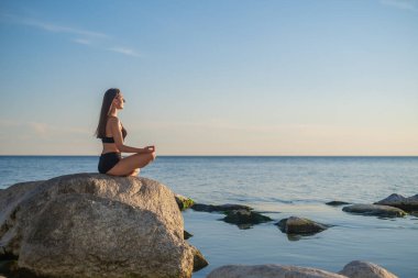 Akşamları deniz kenarında meditasyon yapan bir kadın