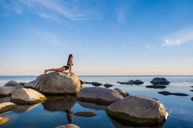 Taş üstünde Corba pozu veren formda bir kadın.