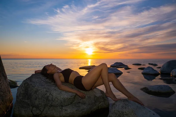 Mulher magra descansando na praia durante o pôr do sol — Fotografia de Stock