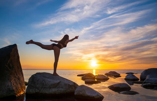 Anonymous woman balancing on stone in Warrior pose