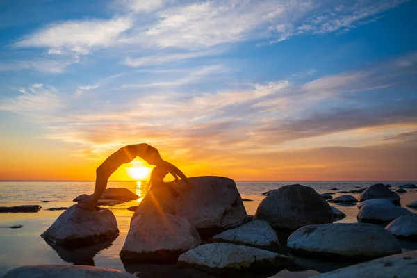 Anonymous female bending back on stones near sea — Stock Photo, Image