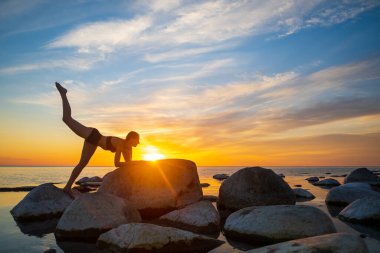 Sıska kadın, gün batımına karşı yoga yapıyor.