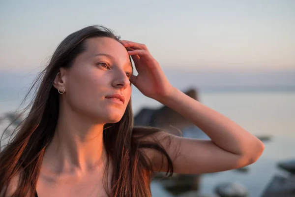 Мрійлива жінка торкається волосся біля моря — стокове фото