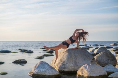 İnce kadın taşın üstünde Vahşi Şey pozu veriyor.