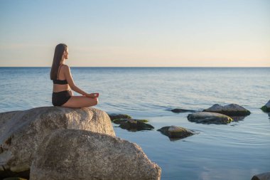 Akşamları deniz kenarında meditasyon yapan bir kadın
