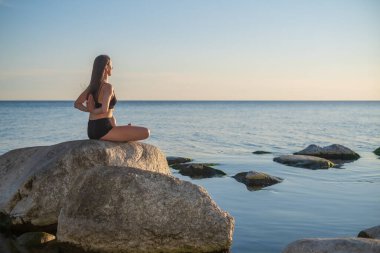 Akşamları deniz kenarında meditasyon yapan bir kadın