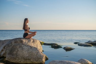 Akşamları deniz kenarında meditasyon yapan bir kadın