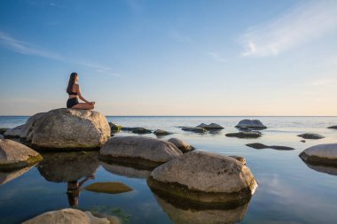 Akşamları deniz kenarında meditasyon yapan bir kadın