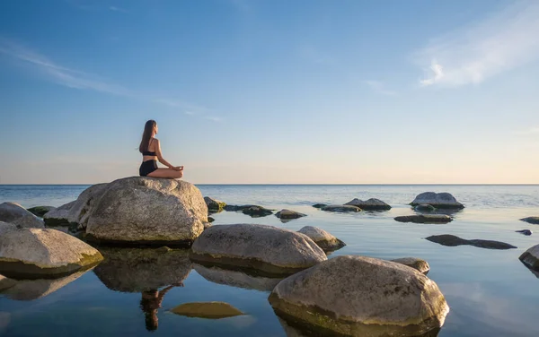 Женщина медитирует вечером у моря — стоковое фото