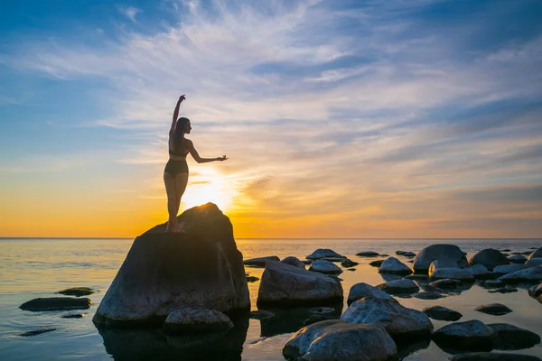 Mulher graciosa dançando em pedra durante o pôr do sol — Fotografia de Stock