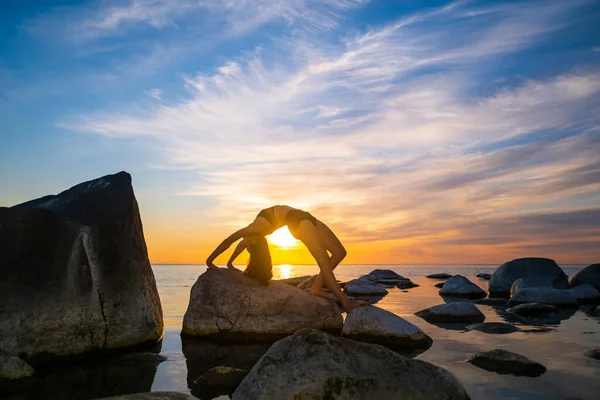 Anonymous female bending back on stones near sea — Stock Photo, Image