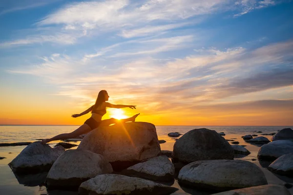 Jovem mulher fazendo rachaduras em pedras durante o pôr do sol — Fotografia de Stock