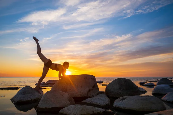 Smal kvinna som gör yoga mot klar solnedgång himmel — Stockfoto